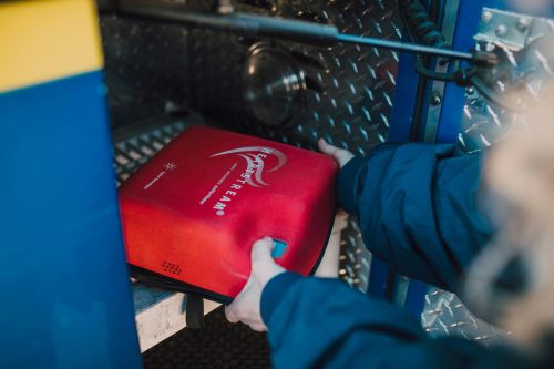 Close-up of an emergency defibrillator being placed in a fire truck compartment.