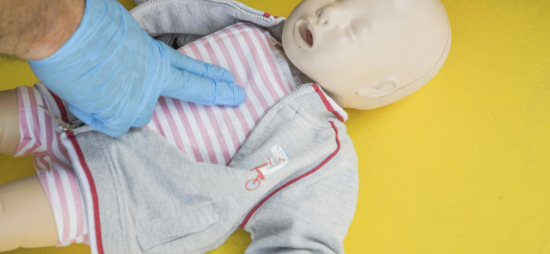 A person demonstrates infant CPR on a manikin, highlighting first aid techniques.