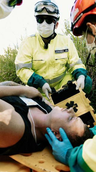 Emergency responders in action assisting a patient outdoors during a medical simulation.