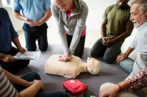 Hands demonstrating CPR technique on a training mannequin with AED.